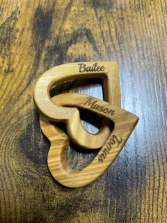 Two sizes of olive wood connected hearts showing engraved names